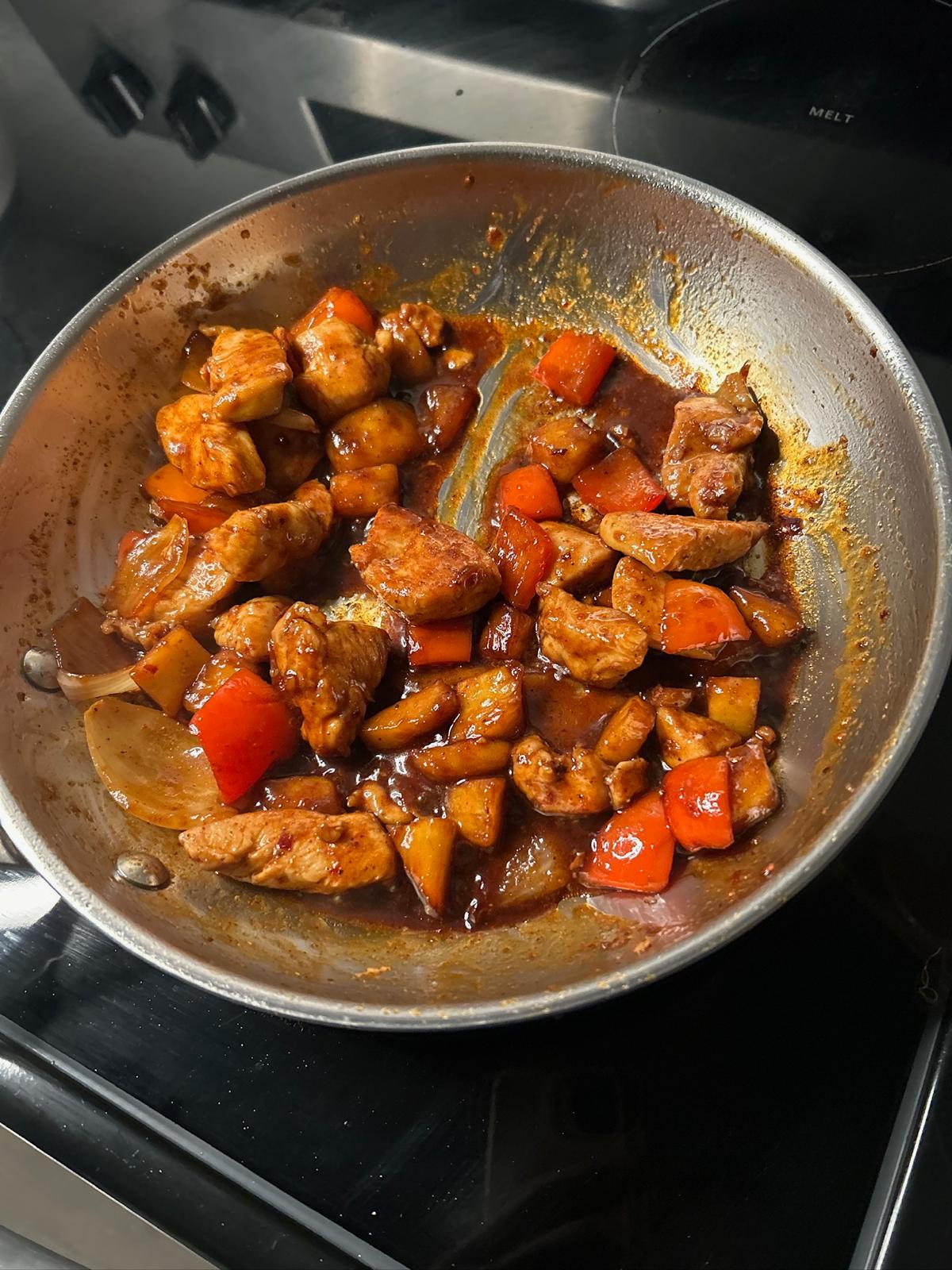 Chicken and peppers cooking in a skillet